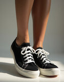 pikaso_texttoimage_photo-of-a-womans-feet-wearing-black-Keds-sneakers.jpeg