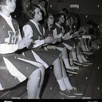 1960s-historical-high-school-femalel-teenage-cheerleaders-in-their-uniforms-sitting-on-the-cou...jpg