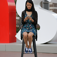 freepik__img1-issitting-on-a-high-stool-looking-at-her-phon__31704.png